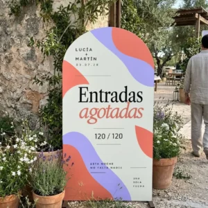Cartel de bienvenida en arco «Entradas agotadas» con los nombres Lucía y Martín y el aforo 120 / 120, de pie a la entrada de la boda